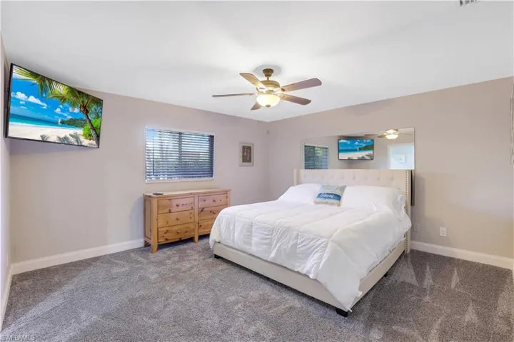 Carpeted bedroom with ceiling fan and baseboards