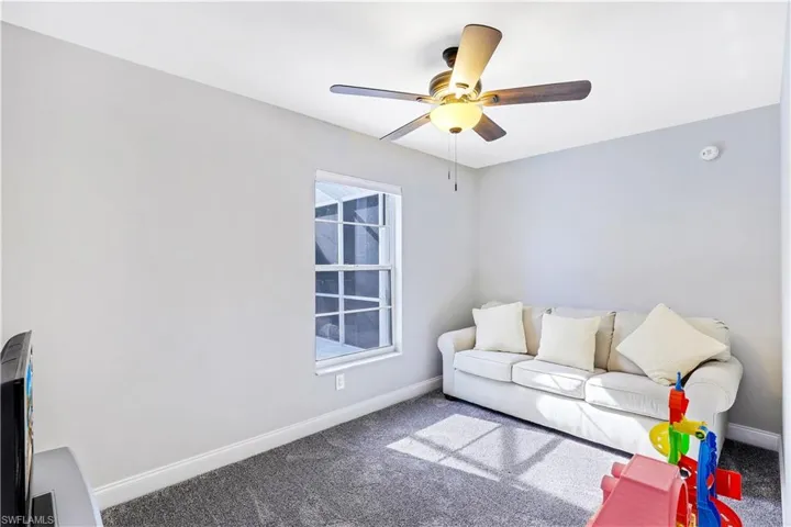 Carpeted living room featuring baseboards and ceiling fan