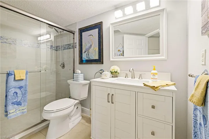 Bathroom with vanity, a textured ceiling, a stall shower, and light tile patterned flooring