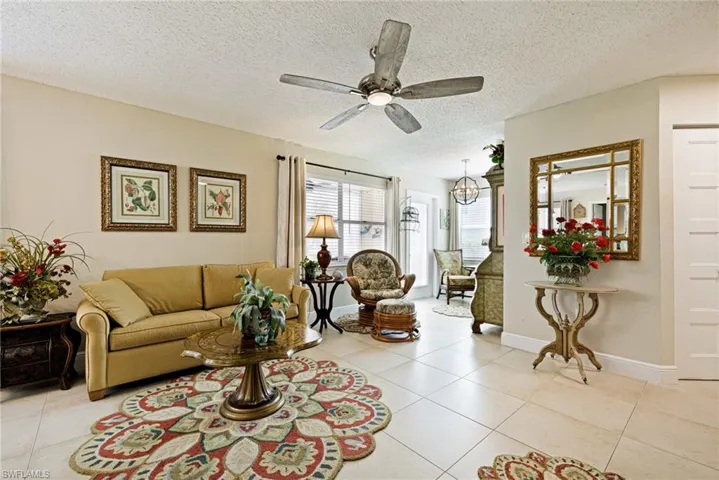 Living area with ceiling fan, light tile patterned flooring, a textured ceiling, and a chandelier