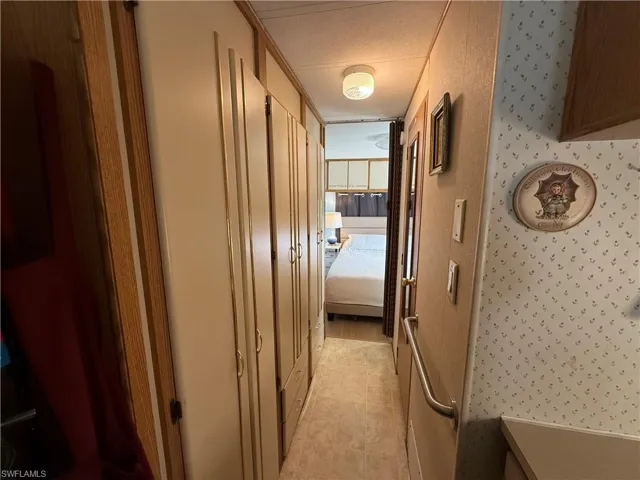 Hallway with wallpapered walls, light tile patterned flooring, and a textured ceiling