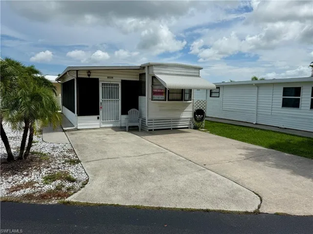 View of front of property featuring a sunroom and driveway
