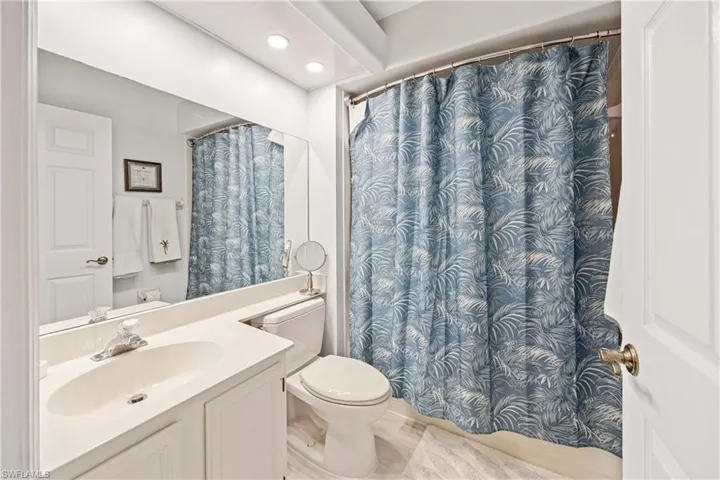 Full bath with toilet, vanity, recessed lighting, and curtained shower