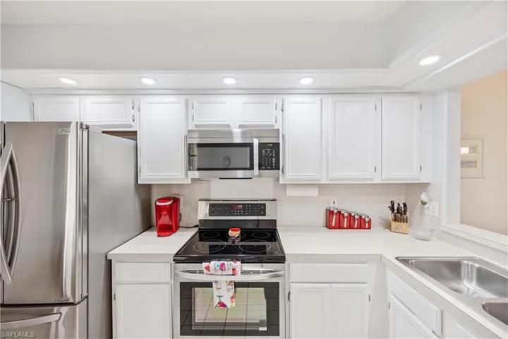 Kitchen featuring appliances with stainless steel finishes, light countertops, white cabinets, recessed lighting, and backsplash