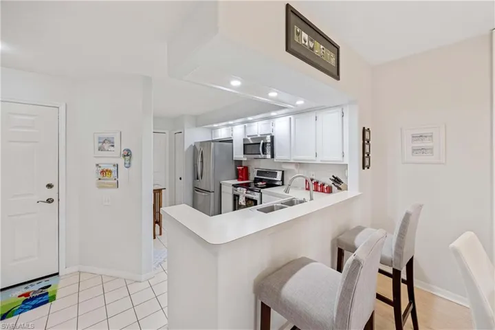 Kitchen featuring stainless steel appliances, a sink, light countertops, baseboards, and a breakfast bar