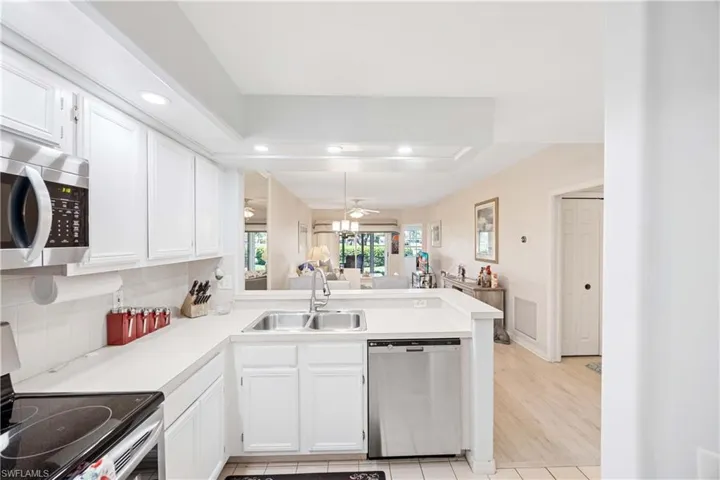 Kitchen featuring stainless steel appliances, a peninsula, a sink, recessed lighting, and light countertops