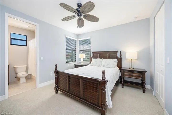 Carpeted bedroom with connected bathroom and ceiling fan
