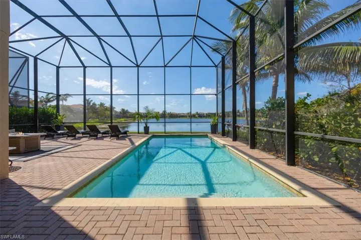 View of pool with a water view, a patio, and glass enclosure
