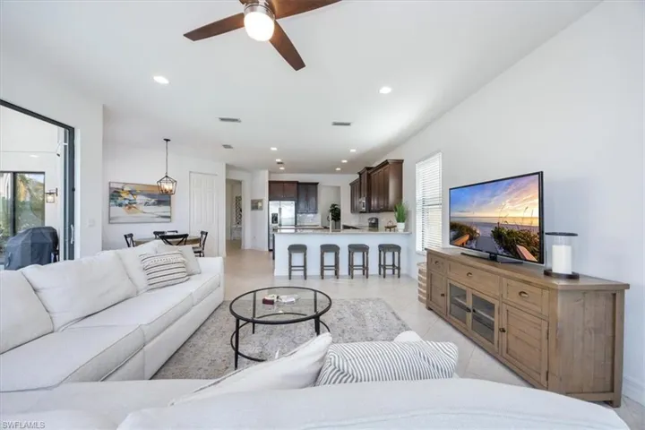 Living room with light tile patterned flooring, a healthy amount of sunlight, and ceiling fan