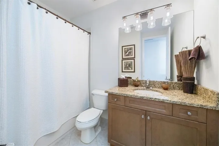 Bathroom with toilet, walk in shower, vanity, and tile patterned floors