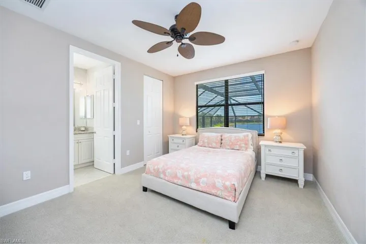 Carpeted bedroom featuring ensuite bath and ceiling fan