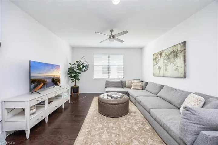 Living room featuring dark wood-type flooring and ceiling fan