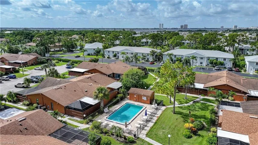 Community pool with surrounding patio, fenced perimeter, and nearby manicured green space
