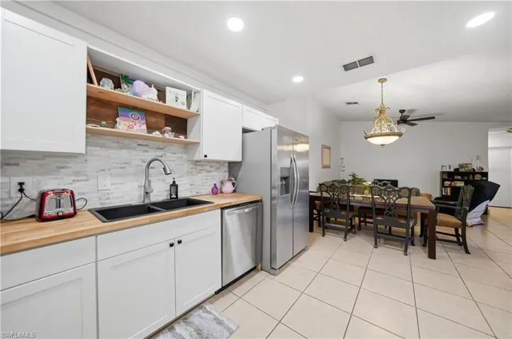 Kitchen featuring white cabinetry, butcher block countertops, and a subway tile backsplash