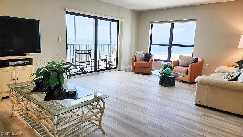 Living area featuring light wood look plank luxury vinyl floors, hurricane rated slider to beachfront balcony and large picture windows to add even more coastal natural light to this relaxing resort style beach retreat!