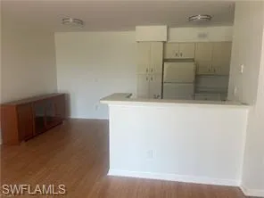 Kitchen featuring freestanding refrigerator, dark wood finished floors, and a peninsula