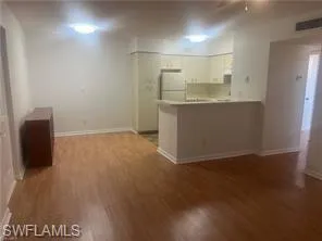 Kitchen with a peninsula, dark wood-style floors, light countertops, and freestanding refrigerator