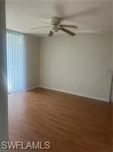 Empty room with dark wood finished floors and a ceiling fan