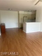 Unfurnished living room with a ceiling fan and dark wood-style flooring