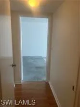 Hall featuring dark wood-style flooring and baseboards