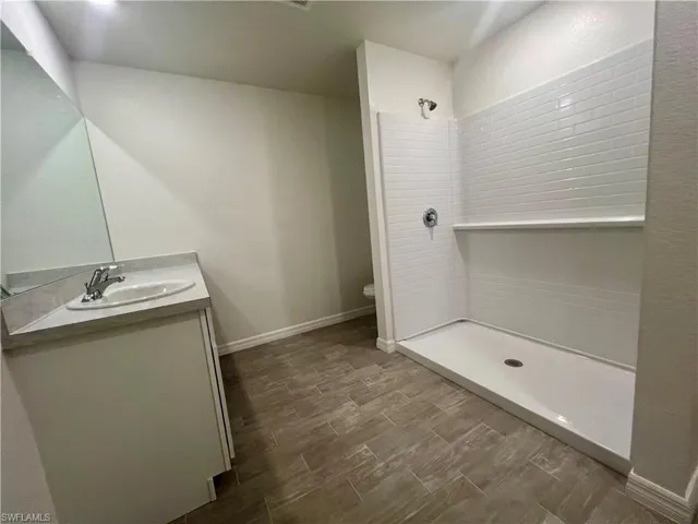 Bathroom with a tile shower, vanity, and wood tiled floors