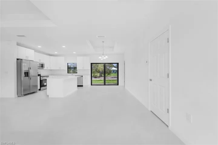 Kitchen featuring appliances with stainless steel finishes, white cabinets, a chandelier, a raised ceiling, and decorative light fixtures