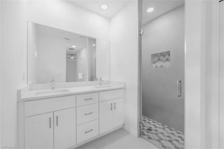 Bathroom with a stall shower, double vanity, recessed lighting, and light tile patterned flooring