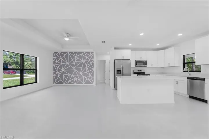 Kitchen with open floor plan, white cabinetry, a center island, appliances with stainless steel finishes, and recessed lighting