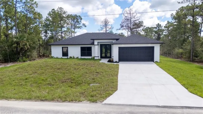 View of front of house featuring a front lawn, stucco siding, and concrete driveway