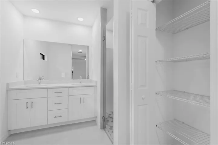 Bathroom featuring double vanity, a closet, a shower stall, light tile patterned flooring, and recessed lighting