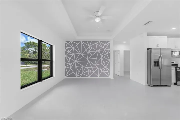 Unfurnished living room with concrete floors, a ceiling fan, and a tray ceiling