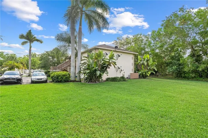Expansive green lawn with established palm trees and dense perimeter foliage