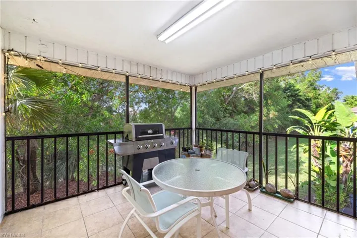 Screened-in patio with tile flooring, a built-in outdoor lighting fixture, and a black metal railing
