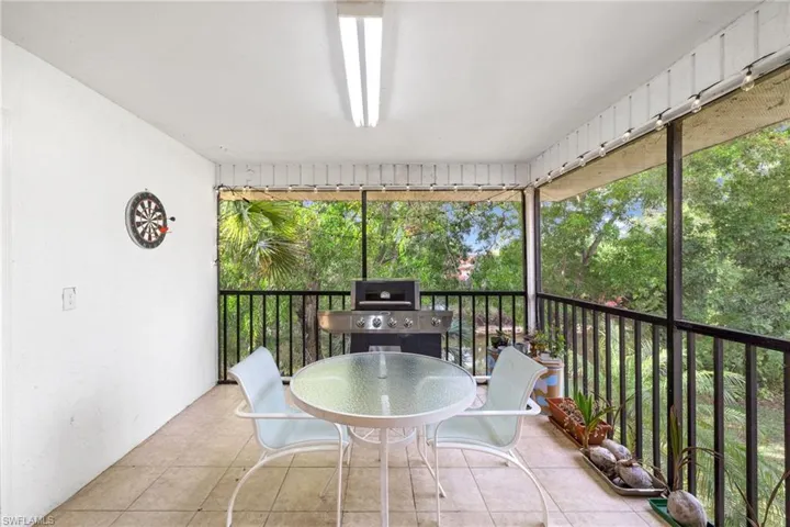 Screened balcony featuring tiled flooring, a white ceiling with a single light fixture, and black railings