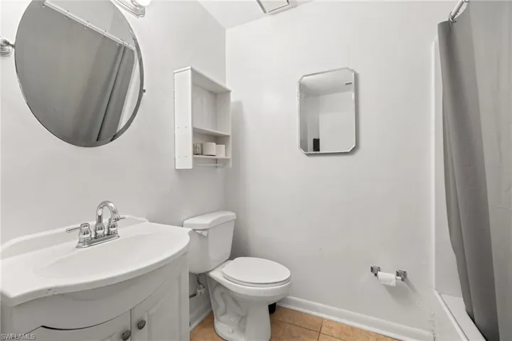 White vanity with integrated sink, chrome faucet, and round mirror