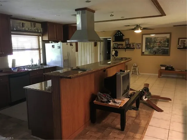 Kitchen featuring a sink, a kitchen breakfast bar, exhaust hood, dishwasher, and ceiling fan