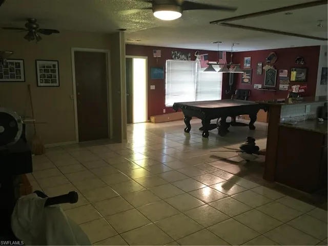 Game room featuring a textured ceiling, pool table, light tile patterned floors, and ceiling fan
