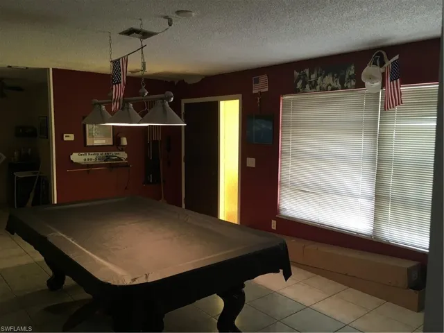 Rec room with a textured ceiling, pool table, and tile patterned flooring