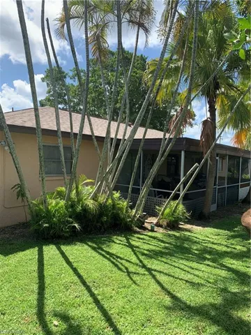 Rear view of house with stucco siding, a yard, and a sunroom