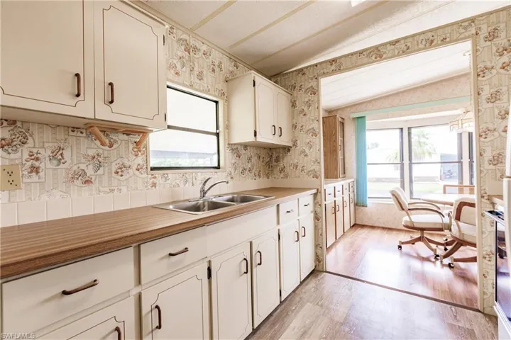 Kitchen with sink, light wood-type flooring, lofted ceiling, and white cabinetry