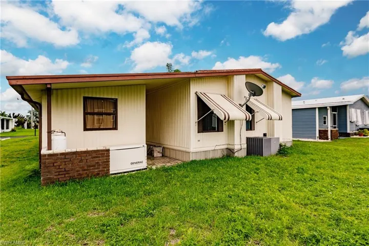 Back of property with central AC and a lawn