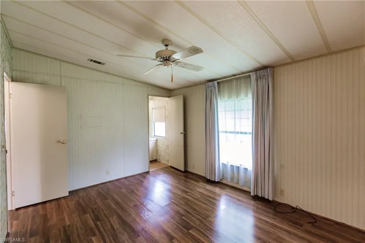 Spare room with lofted ceiling, wood-type flooring, and ceiling fan