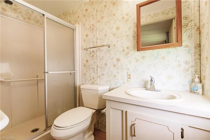 Bathroom featuring a shower with shower door, vanity, and toilet