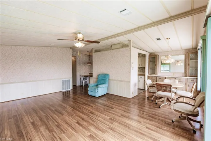 Sitting room featuring ceiling fan with notable chandelier, vaulted ceiling with beams, and light wood-type flooring