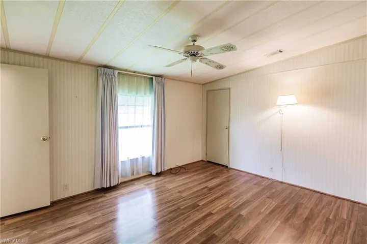 Empty room featuring lofted ceiling, wood-type flooring, and ceiling fan