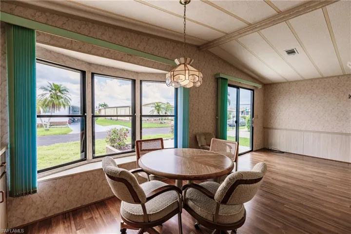 Dining area with hardwood / wood-style flooring, vaulted ceiling, a wealth of natural light, and a textured ceiling