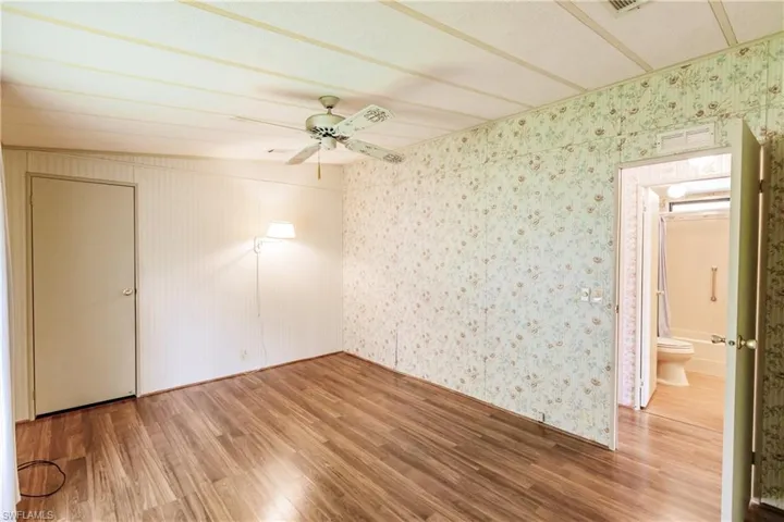 Unfurnished room featuring wood-type flooring, ceiling fan, and lofted ceiling