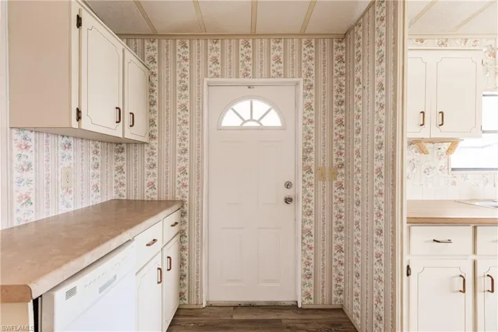 Kitchen with white cabinetry, white dishwasher, and hardwood / wood-style floors