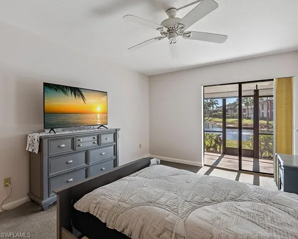 Bedroom with light colored carpet, a water view, ceiling fan, and access to exterior