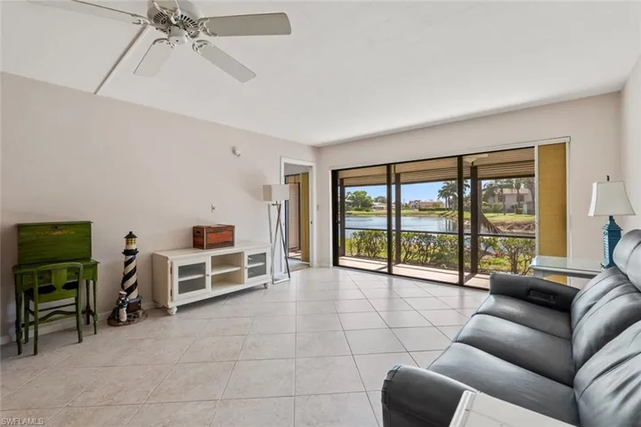 Living room with a water view, ceiling fan, and light tile flooring